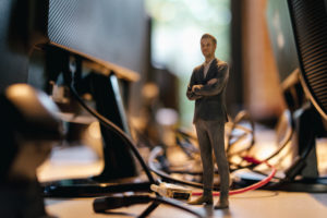 Businessman figurine standing amidst computer cables