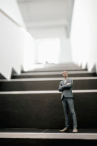 Businessman figurine standing on stairs in office