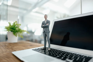 Businessman figurine standing on laptop in modern office