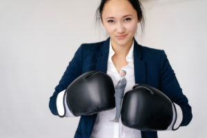 Businesswoman holding businessman figurine between boxing gloves