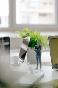 Businessman figurine standing on desk with mobile devices