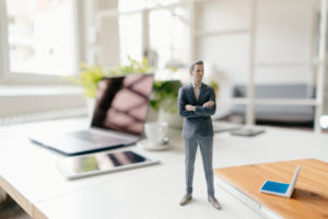 Businessman figurine standing on a desk with mobile devices