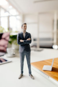 Businessman figurine standing on a desk with mobile devices