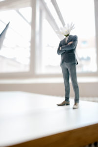 Businessman figurine with a flower head standing on desk