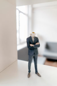 Businessman figurine with coffee cup head standing in office