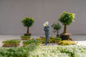 Businessman figurine with flower head standing park