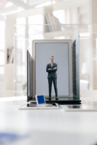 Businessman figurine standing on portable devices in a glass cage