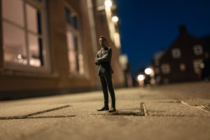 Businessman figurine standing in street in front of houses