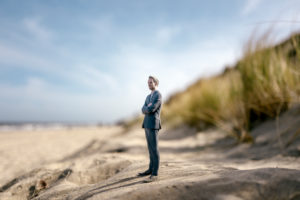 Businessman figurine standing on sand dune, looking at distance