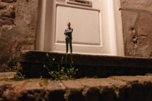 Businessman figurine standing on stairs in front of an entrance door