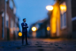 Businessman figurine standing in street in front of houses