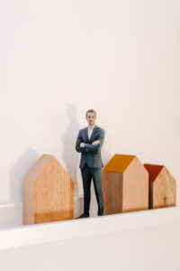 Businessman figurine standing by wooden house models