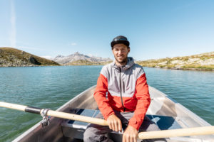 Young smiling man in a rowing boat,Lake Suretta,Graubuenden,Switzerland Young smiling man in a rowing boat,Lake Suretta,Graubuenden,Switzerland
