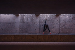 Female athlete warming up before running in pedestrian underpass Female athlete warming up before running in pedestrian underpass