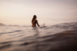 Female surfer sitting on surfboard in the evening, Costa Rica Female surfer sitting on surfboard in the evening, Costa Rica