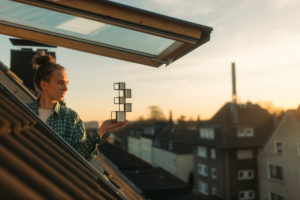 Young woman holding design at the window in the evening Young woman holding design at the window in the evening