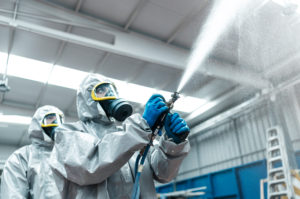 Low angle view of sanitation workers spraying chemical from hose in warehouse Low angle view of sanitation workers spraying chemical from hose in warehouse