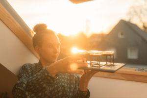 Young woman holding model at the window in backlight Young woman holding model at the window in backlight