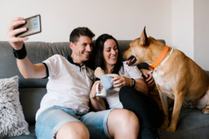 Smiling couple taking selfie with dog at home Smiling couple taking selfie with dog at home
