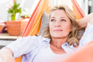 Portrait of pensive mature woman relaxing in hammock Portrait of pensive mature woman relaxing in hammock