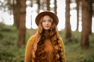 Beautiful woman with long hair wearing hat standing in forest Beautiful woman with long hair wearing hat standing in forest