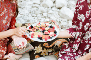 Close-up of woman offering fruits to female friend in picnic Close-up of woman offering fruits to female friend in picnic