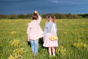 Elementary siblings standing with fresh lemons while standing at rape field on sunny day Elementary siblings standing with fresh lemons while standing at rape field on sunny day