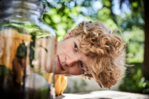 Portrait of young man watching plants in a glass Portrait of young man watching plants in a glass