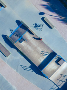 Man sitting on concrete ramp in skate park, aerial view Man sitting on concrete ramp in skate park, aerial view