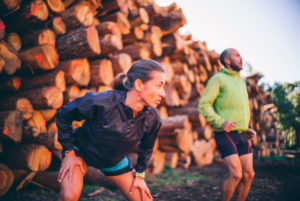 Mature couple exercising while standing against logs Mature couple exercising while standing against logs