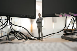 Businessman figurine standing under computer screens