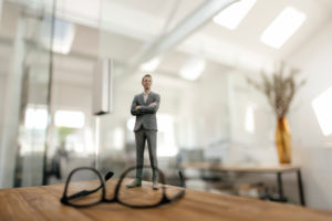 Businessman figurine standing behind glasses on desk in modern office