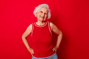 Smiling woman with white hair posing against a red background