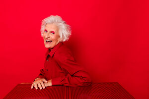 Cheerful woman in red shirt smiling against a vibrant red background