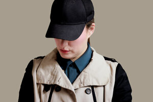 Woman in detective-style clothing looking down wearing a cap
