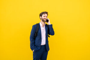 Businessman with backpack smiling while using smartphone