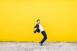 Businessman posing cheerfully against yellow backdrop