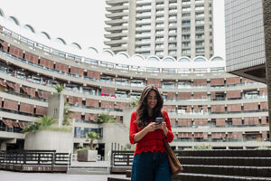 Woman using smartphone outside brutalist building