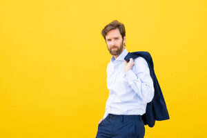 Confident businessman in suit against yellow background