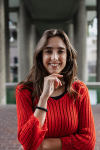 Smiling woman in red sweater standing in urban environment