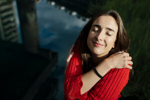 Woman embracing self in a serene outdoor setting