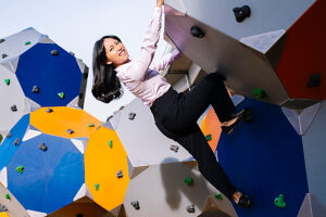 Ambitious businesswoman climbing a bouldering wall