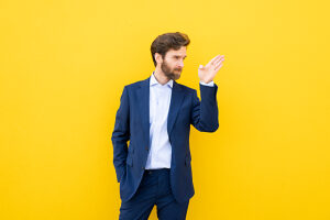 Confident businessman in suit against yellow background