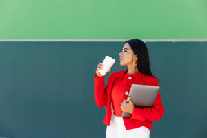 Businesswoman with laptop and coffee standing outdoors