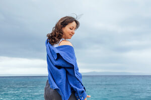 Woman enjoying wind by the sea in casual blue shirt