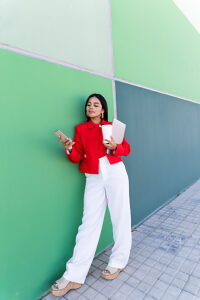 Businesswoman texting on smartphone holding laptop and coffee