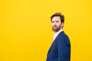 Confident businessman posing against yellow background outdoors