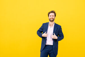 Confident businessman smiling at camera against yellow background