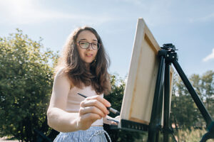 Artist painting outdoors on canvas in park on a sunny day