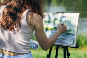 Faceless artist painting landscape outdoors in park setting